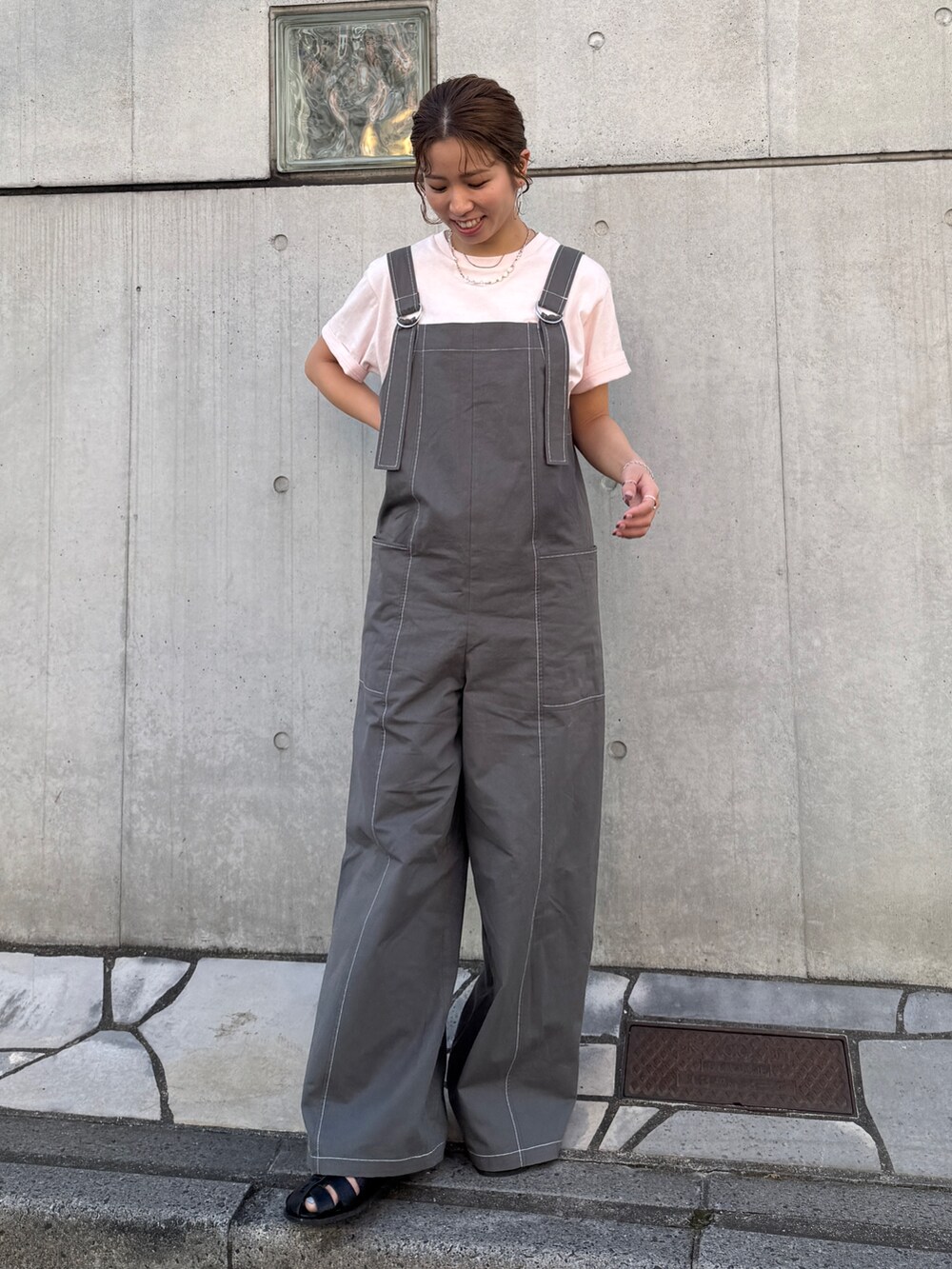 ピンク系のTシャツ/カットソー、ブラック系のサロペット/オーバーオール、ブラック系のサンダルを着用したレディースの春コーディネートの2枚目の写真