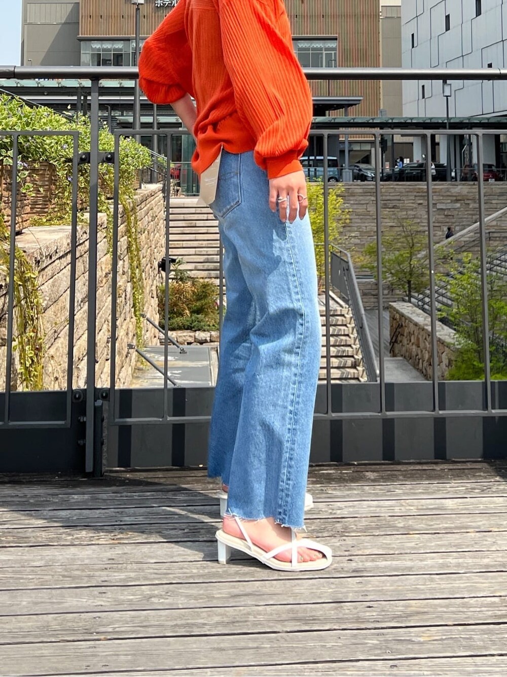 ホワイト系のサンダル、ブルー系のデニムパンツ、オレンジ系のカーディガン/ボレロを着用したレディースの春コーディネートの3枚目の写真