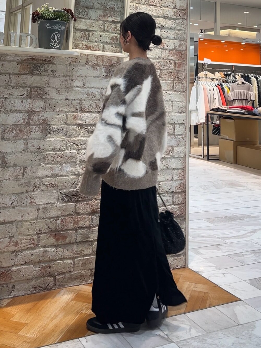 ブラック系のスカート、ブラック系のハンドバッグ、ベージュ系のニット/セーターを着用したレディースの秋コーディネートの3枚目の写真