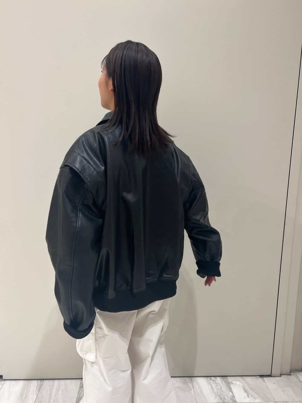 グレー系のニット/セーター、ホワイト系のカーゴパンツ、ブラック系のブルゾンを着用したレディースの秋コーディネートの8枚目の写真