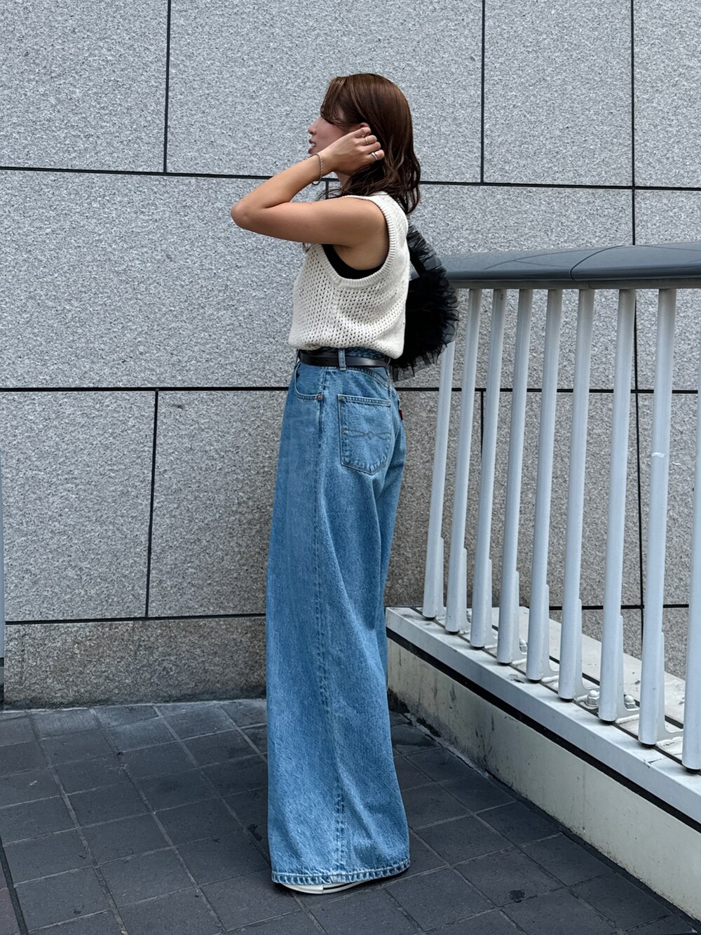 ブルー系のデニムパンツ、ホワイト系のニット/セーター、ブラック系のショルダーバッグを着用したレディースの秋コーディネートの6枚目の写真