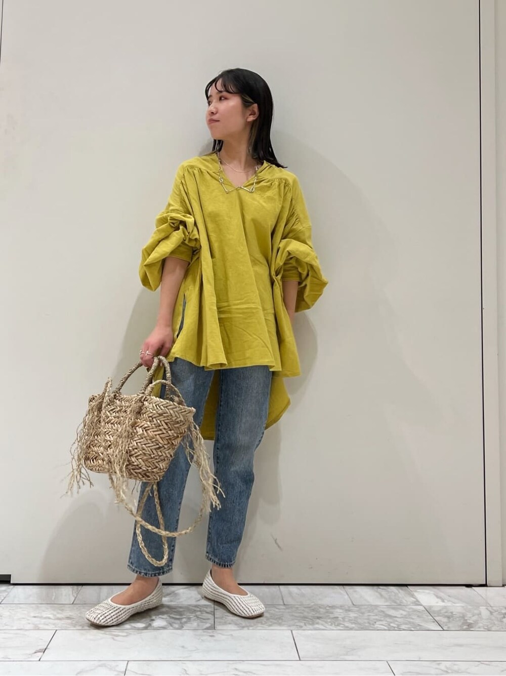 ホワイト系のパンプス、イエロー系のシャツ/ブラウス、ベージュ系のかごバッグを着用したレディースの春コーディネートの2枚目の写真