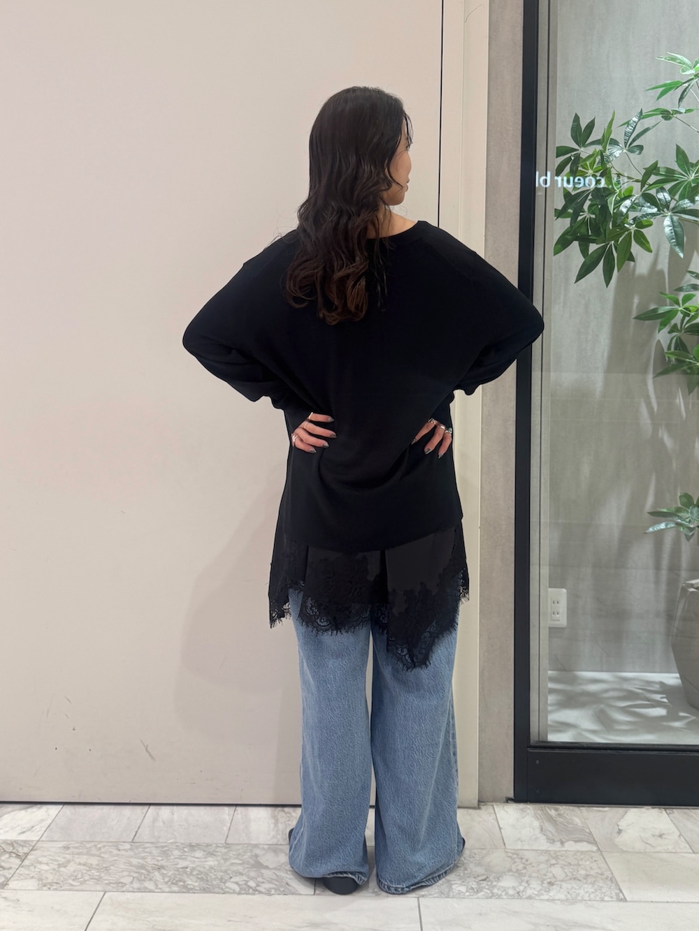 ブラック系のニット/セーター、ブラック系のワンピース、ブルー系のデニムパンツを着用したレディースの秋コーディネートの3枚目の写真