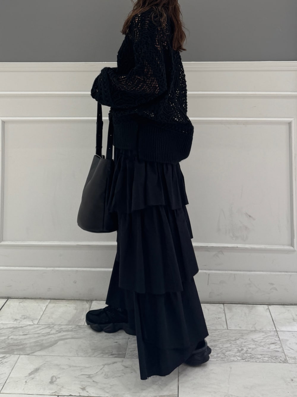 ブラック系のスカート、ブラック系のニット/セーター、ブラック系のショルダーバッグを着用したレディースの冬コーディネートの7枚目の写真