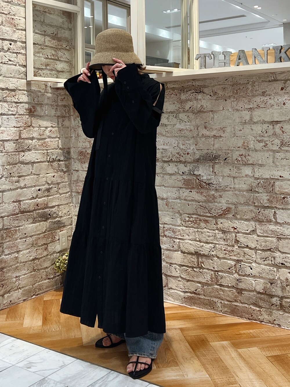 ブルー系のデニムパンツ、ブラック系のサンダル、ブラック系のワンピースを着用したレディースの春コーディネートの2枚目の写真