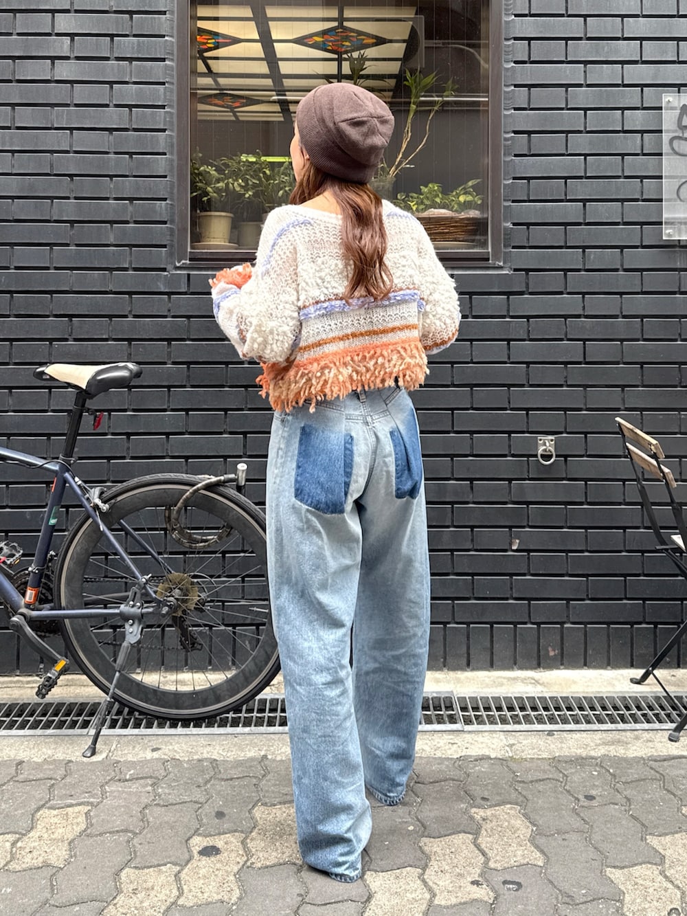 ブルー系のデニムパンツ、ホワイト系のニット/セーター、ブラック系のサンダルを着用したレディースの秋コーディネートの4枚目の写真