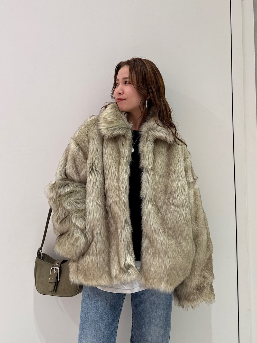 ベージュ系のダウンジャケット/コート、グリーン系のハンドバッグ、ブルー系のデニムパンツを着用したレディースの冬コーディネートの8枚目の写真