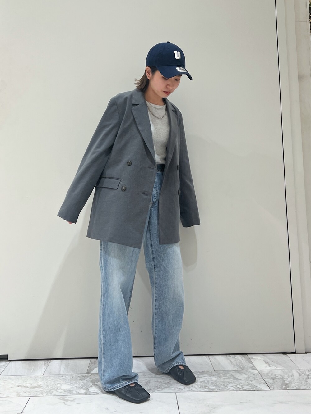 グレー系のテーラードジャケット、ブルー系のデニムパンツ、ブラック系のパンプスを着用したレディースの冬コーディネートの2枚目の写真