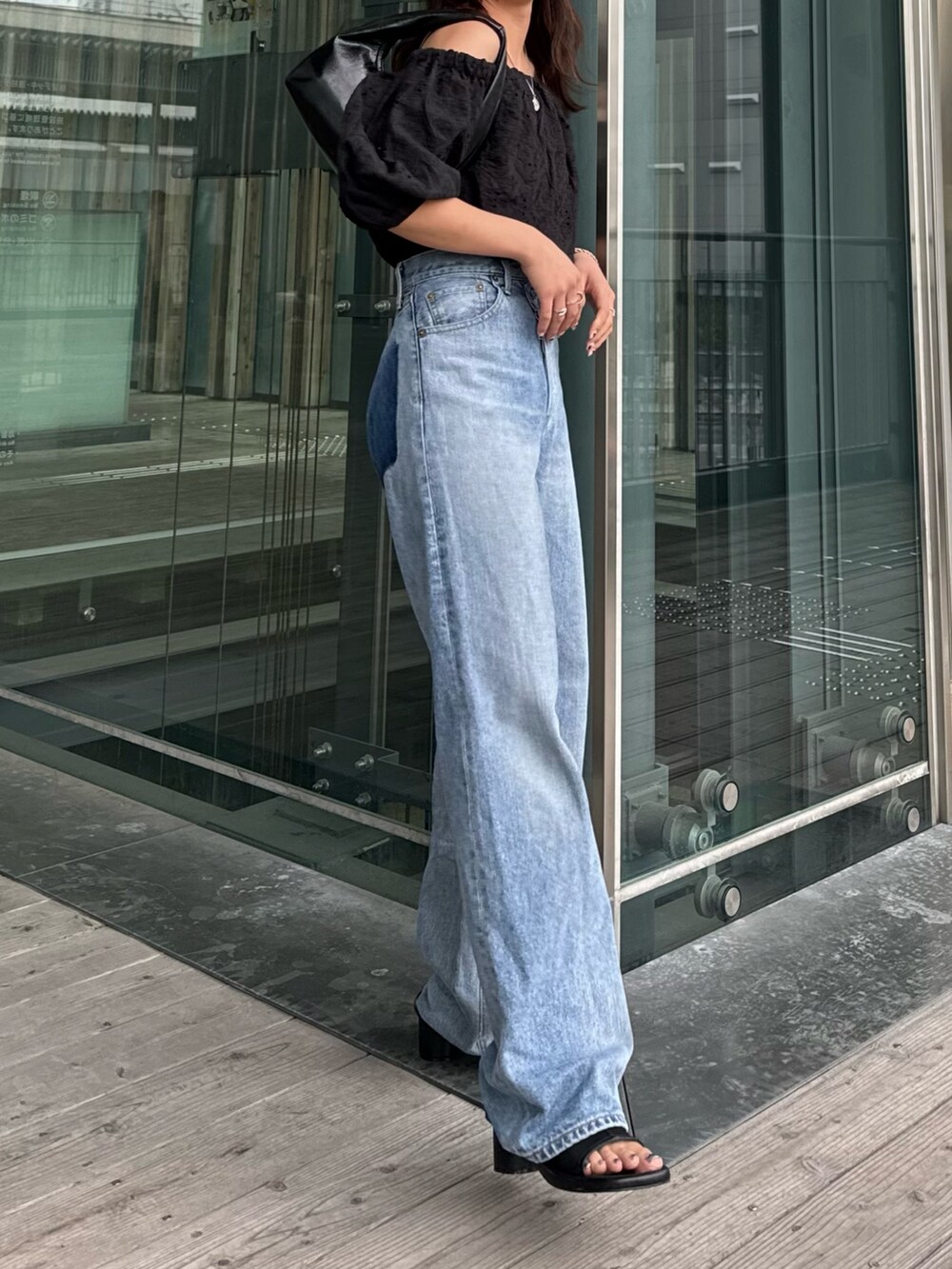 ブルー系のデニムパンツ、ブラック系のシャツ/ブラウス、ブラック系のハンドバッグを着用したレディースの春コーディネートの6枚目の写真