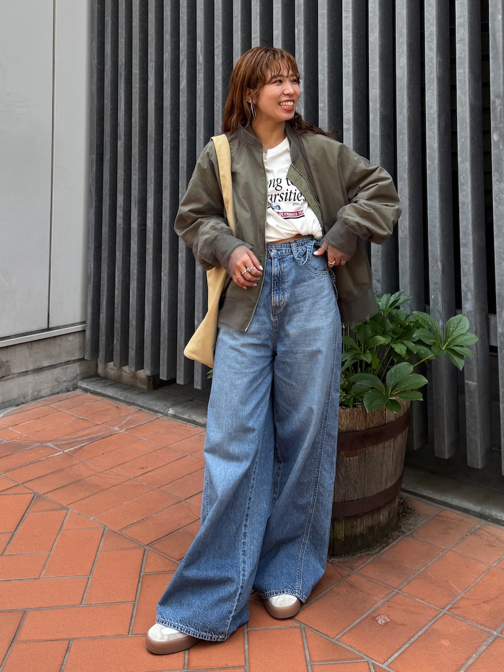 ベージュ系のトートバッグ、ホワイト系のタンクトップ、ブルー系のデニムパンツを着用したレディースの夏コーディネートの2枚目の写真