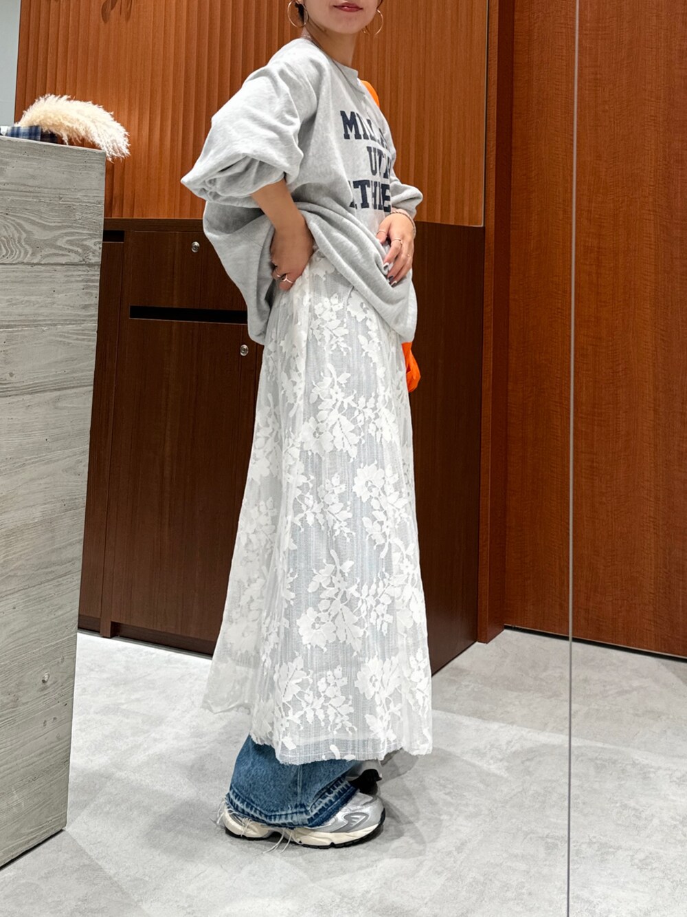 ホワイト系のワンピース、グレー系のスウェット、ブルー系のデニムパンツを着用したレディースの秋コーディネートの3枚目の写真