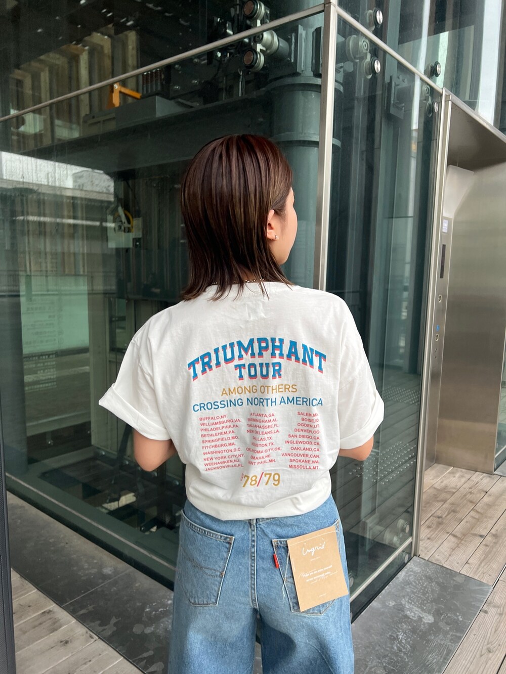 ホワイト系のTシャツ/カットソー、ホワイト系のサンダル、ブルー系のデニムパンツを着用したレディースの春コーディネートの6枚目の写真