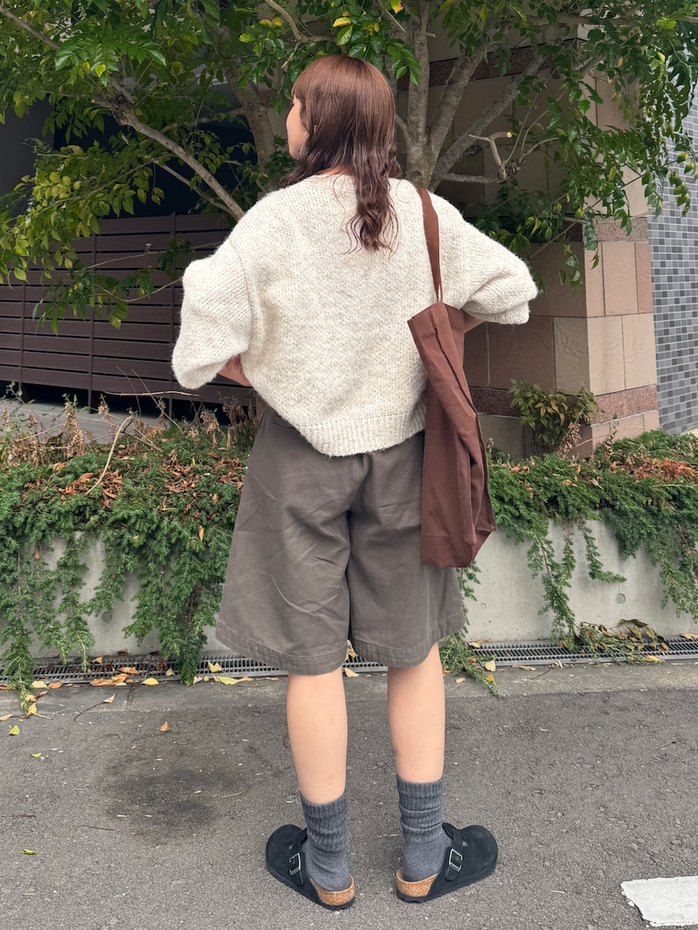 グレー系のチノパンツ、ホワイト系のニット/セーター、ブラウン系のトートバッグを着用したレディースの秋コーディネートの5枚目の写真