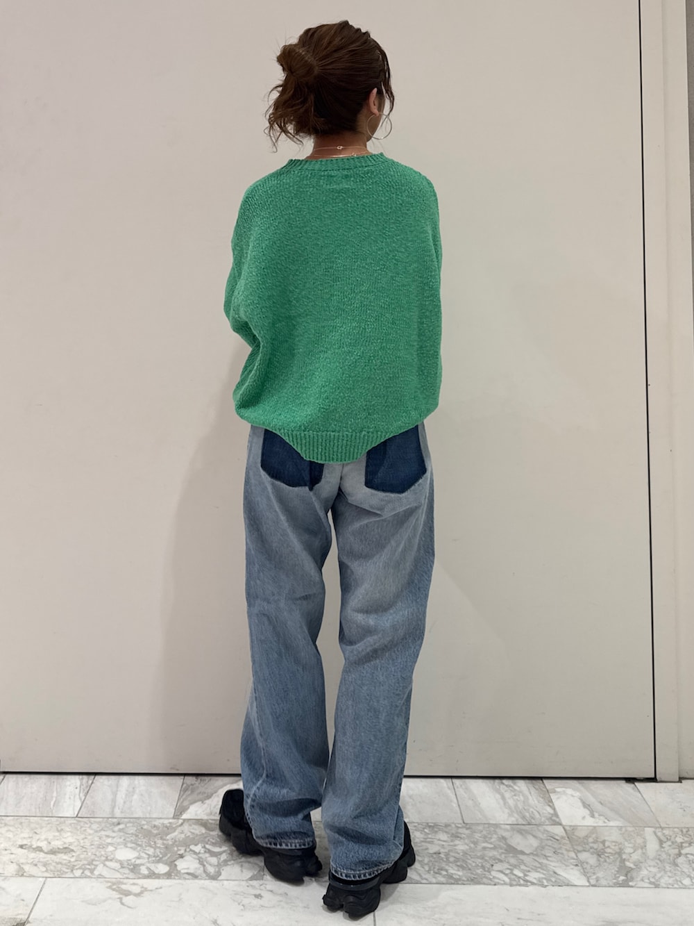 ブルー系のデニムパンツ、グリーン系のニット/セーター、シルバー系のネックレスを着用したレディースの冬コーディネートの4枚目の写真