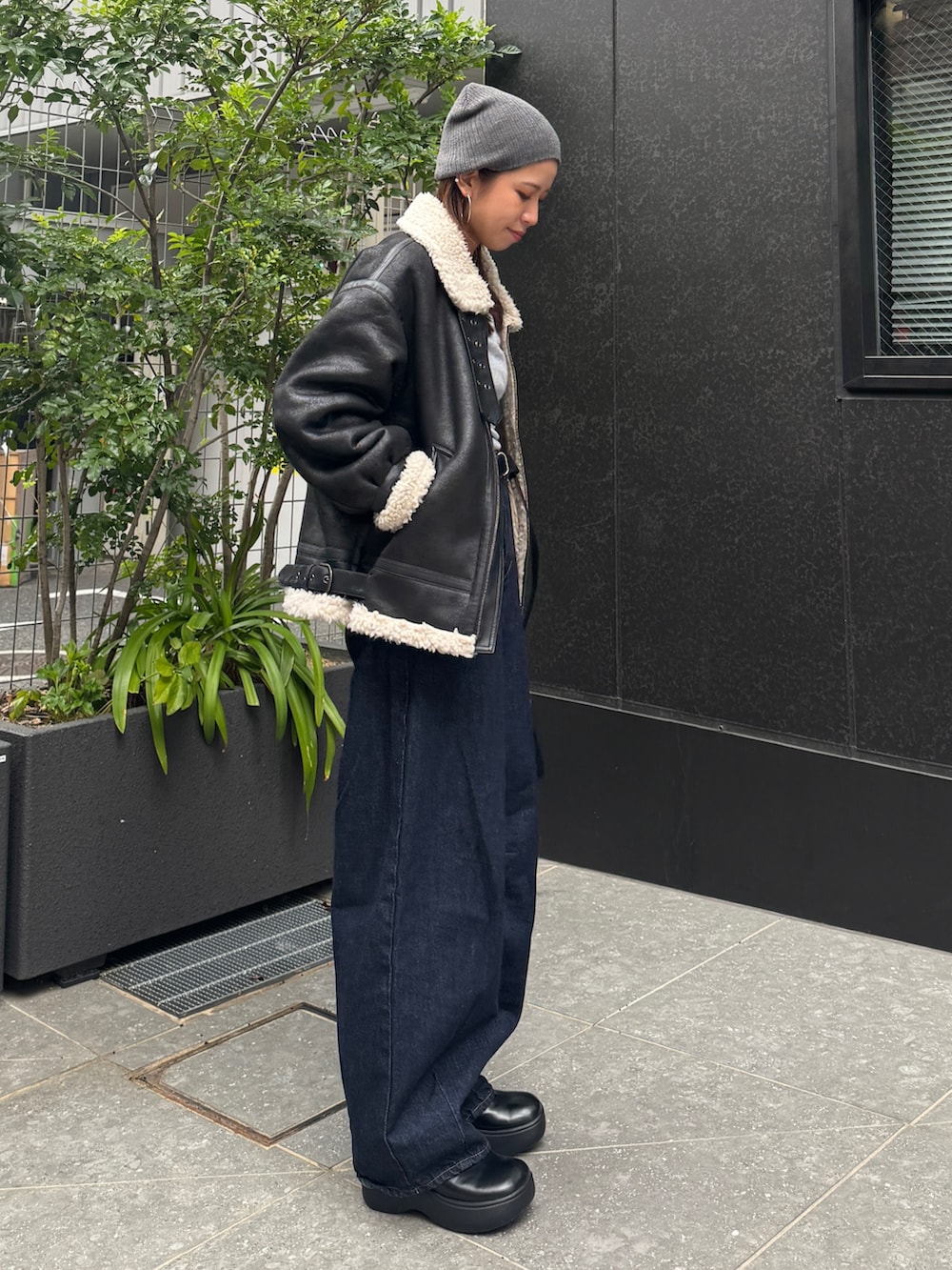 ブラック系のブルゾン、ブルー系のデニムパンツ、グレー系のニット/セーターを着用したレディースの秋コーディネートの3枚目の写真