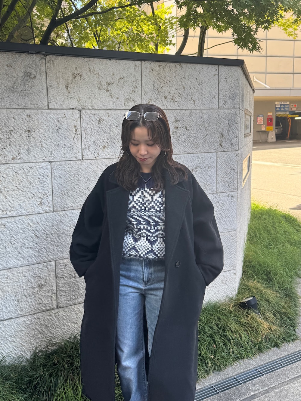 ブルー系のデニムパンツ、ブルー系のニット/セーター、ブラック系のチェスターコートを着用したレディースの秋コーディネートの9枚目の写真