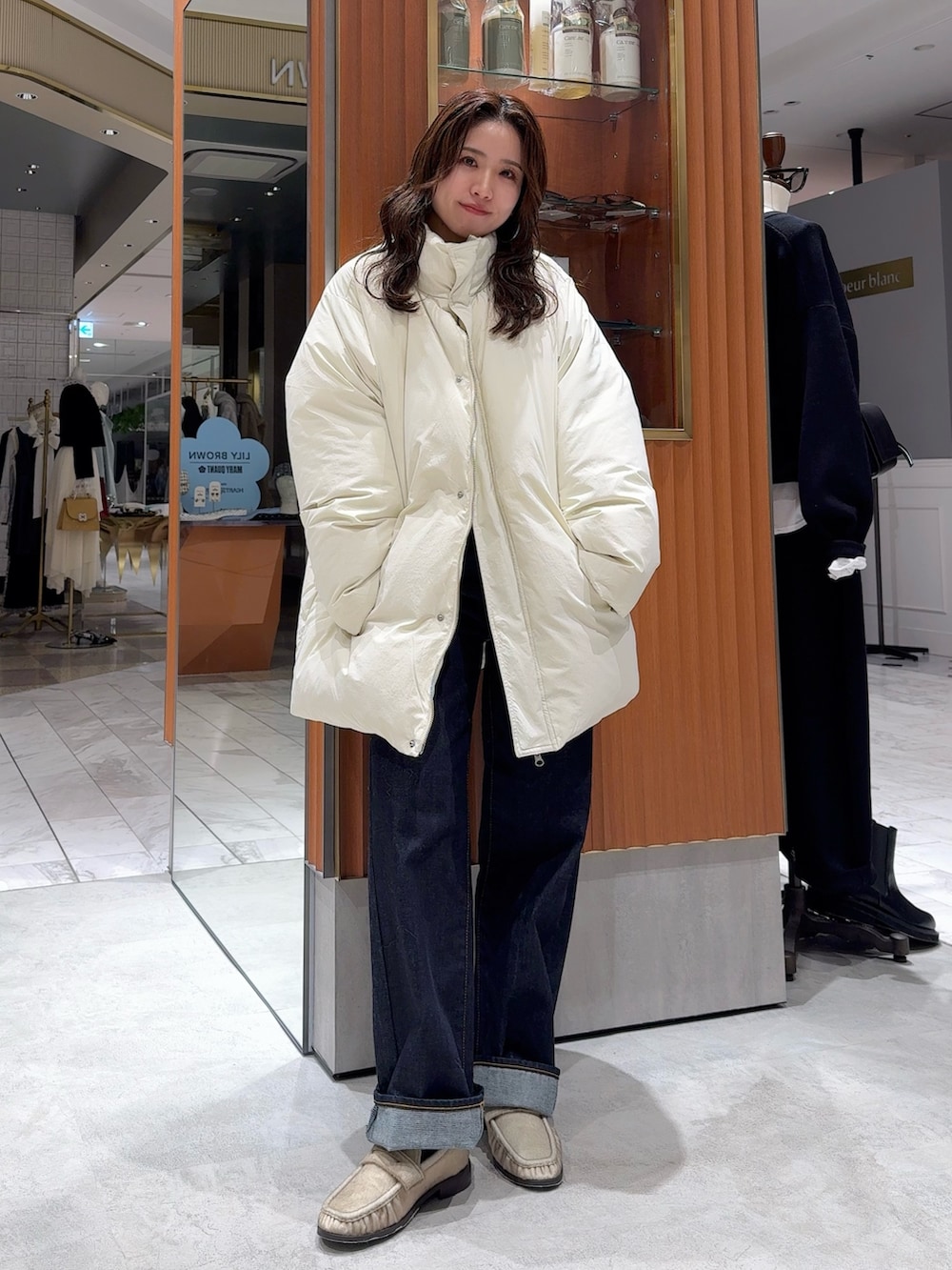 ホワイト系のダウンジャケット/コート、グレー系のニット/セーター、ブルー系のデニムパンツを着用したレディースの冬コーディネートの8枚目の写真