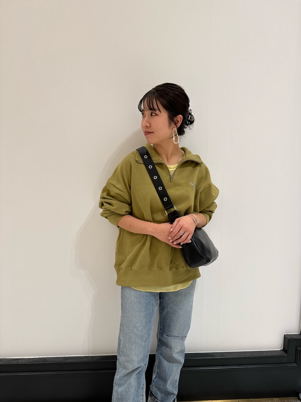 グリーン系のスウェット、ブラック系のショルダーバッグ、イエロー系のTシャツ/カットソーを着用したレディースの冬コーディネートの3枚目の写真