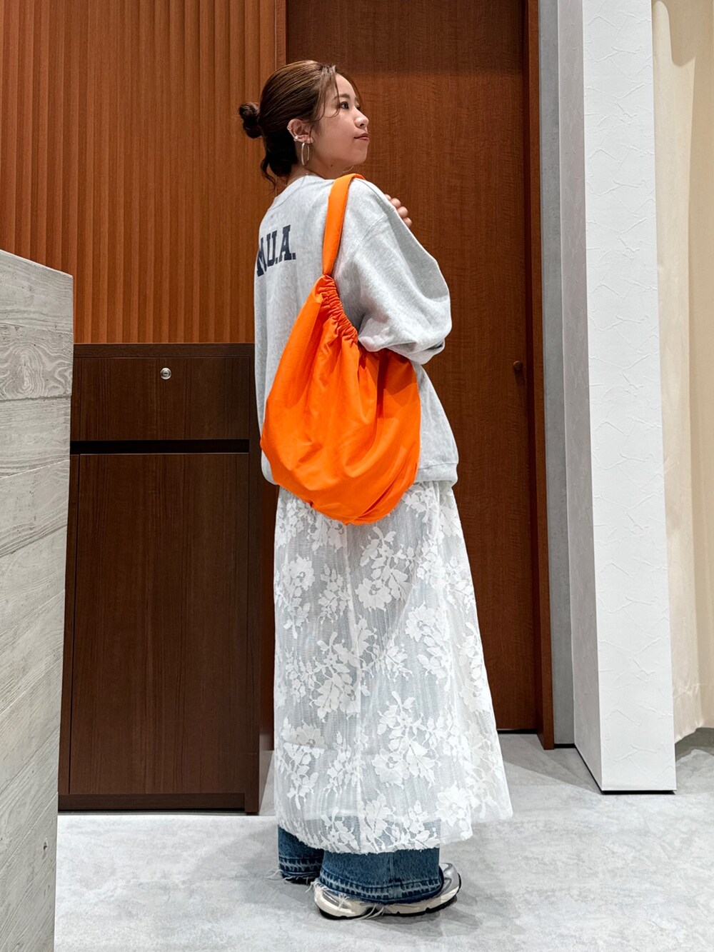 ホワイト系のワンピース、グレー系のスウェット、ブルー系のデニムパンツを着用したレディースの秋コーディネートの6枚目の写真