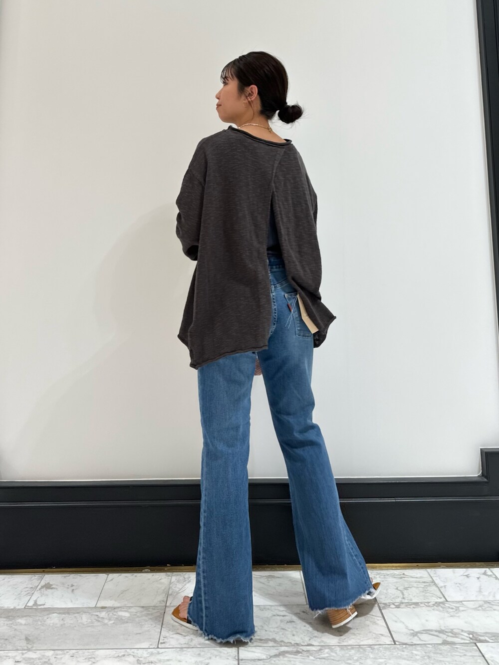 グレー系のニット/セーター、ブルー系のデニムパンツ、ブラック系のサンダルを着用したレディースの春コーディネートの6枚目の写真