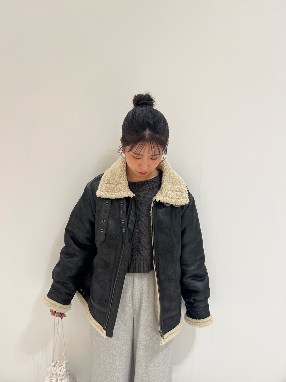 ホワイト系のハンドバッグ、グレー系のニット/セーター、ブラック系のムートンコートを着用したレディースの冬コーディネートの7枚目の写真