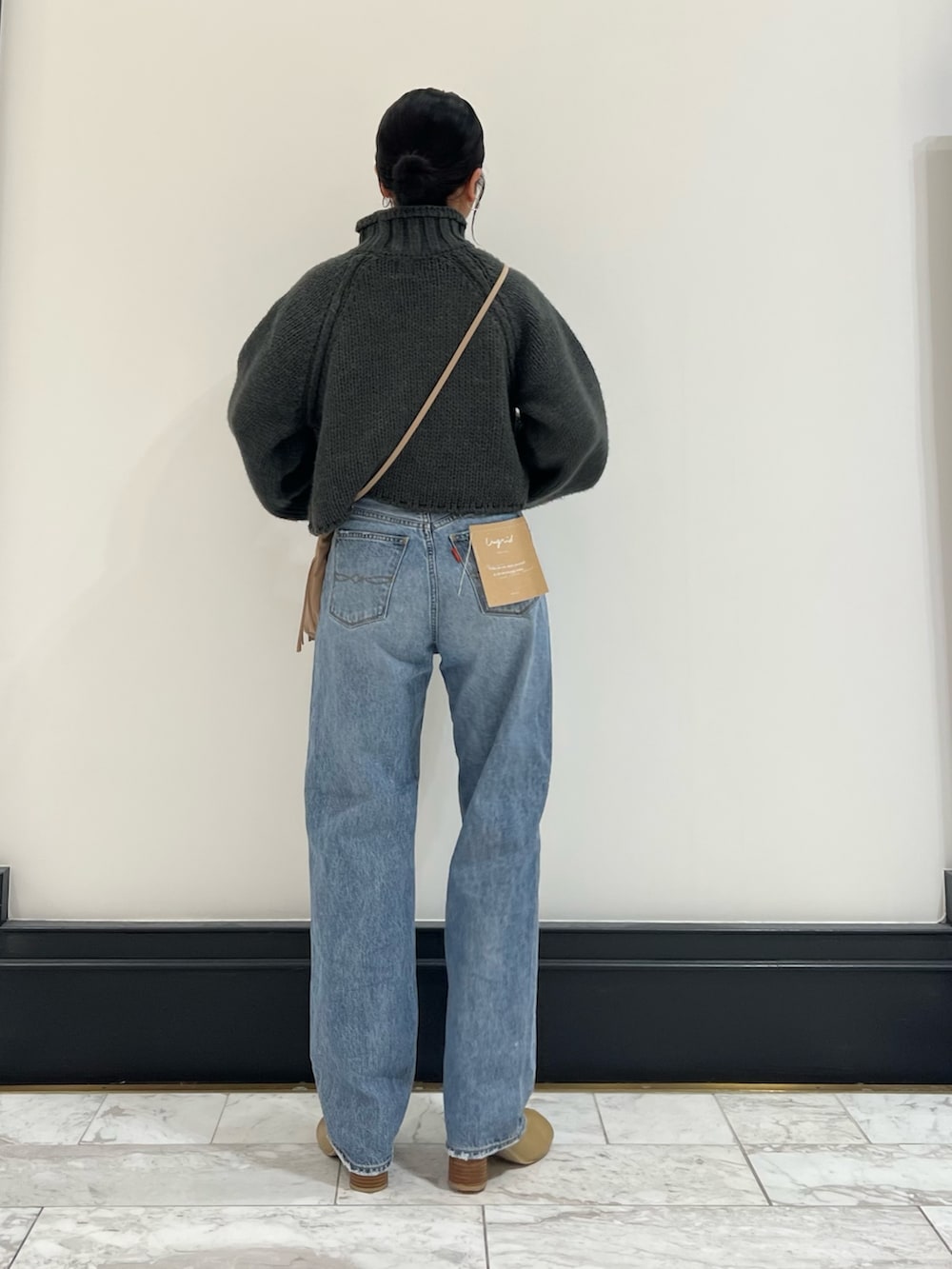 ブルー系のデニムパンツ、グレー系のニット/セーター、ベージュ系のブーツを着用したレディースの秋コーディネートの4枚目の写真