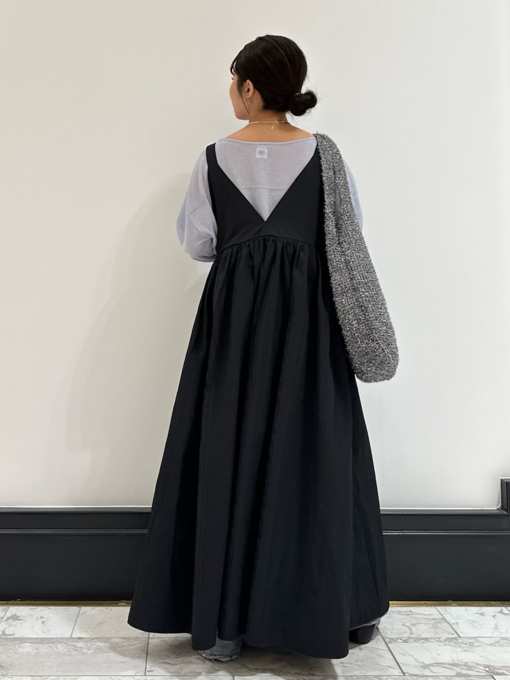 ブラック系のワンピース、ブルー系のニット/セーター、ブルー系のデニムパンツを着用したレディースの春コーディネートの3枚目の写真