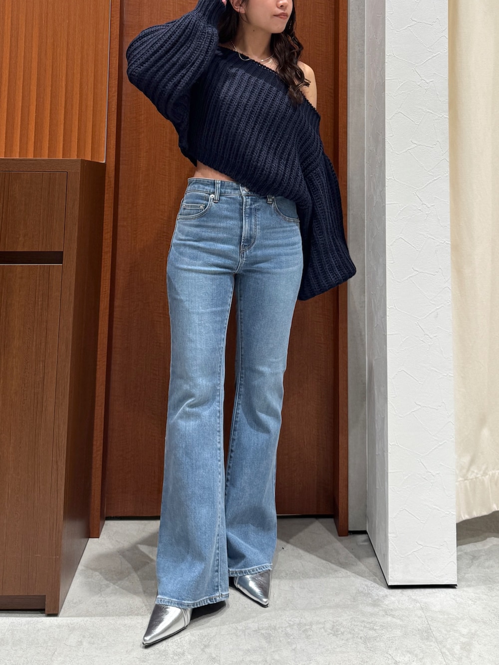 ブルー系のニット/セーター、ブルー系のデニムパンツ、シルバー系のパンプスを着用したレディースの秋コーディネートの2枚目の写真