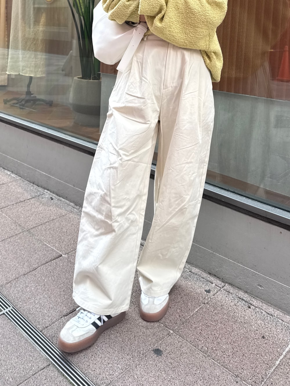 ホワイト系のチノパンツ、グリーン系のニット/セーター、ホワイト系のショルダーバッグを着用したレディースの冬コーディネートの8枚目の写真