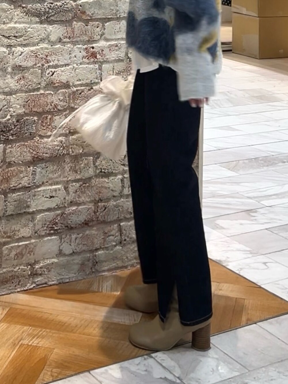 ブルー系のニット/セーター、ホワイト系のハンドバッグ、ブルー系のデニムパンツを着用したレディースの秋コーディネートの4枚目の写真