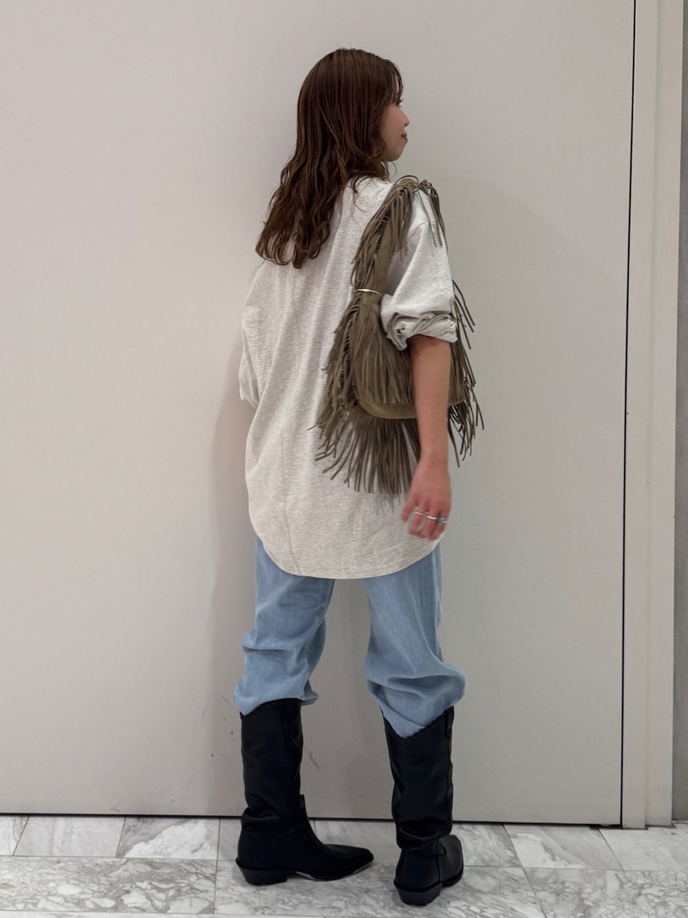 グレー系のTシャツ/カットソー、ベージュ系のハンドバッグ、ブルー系のデニムパンツを着用したレディースの春コーディネートの4枚目の写真