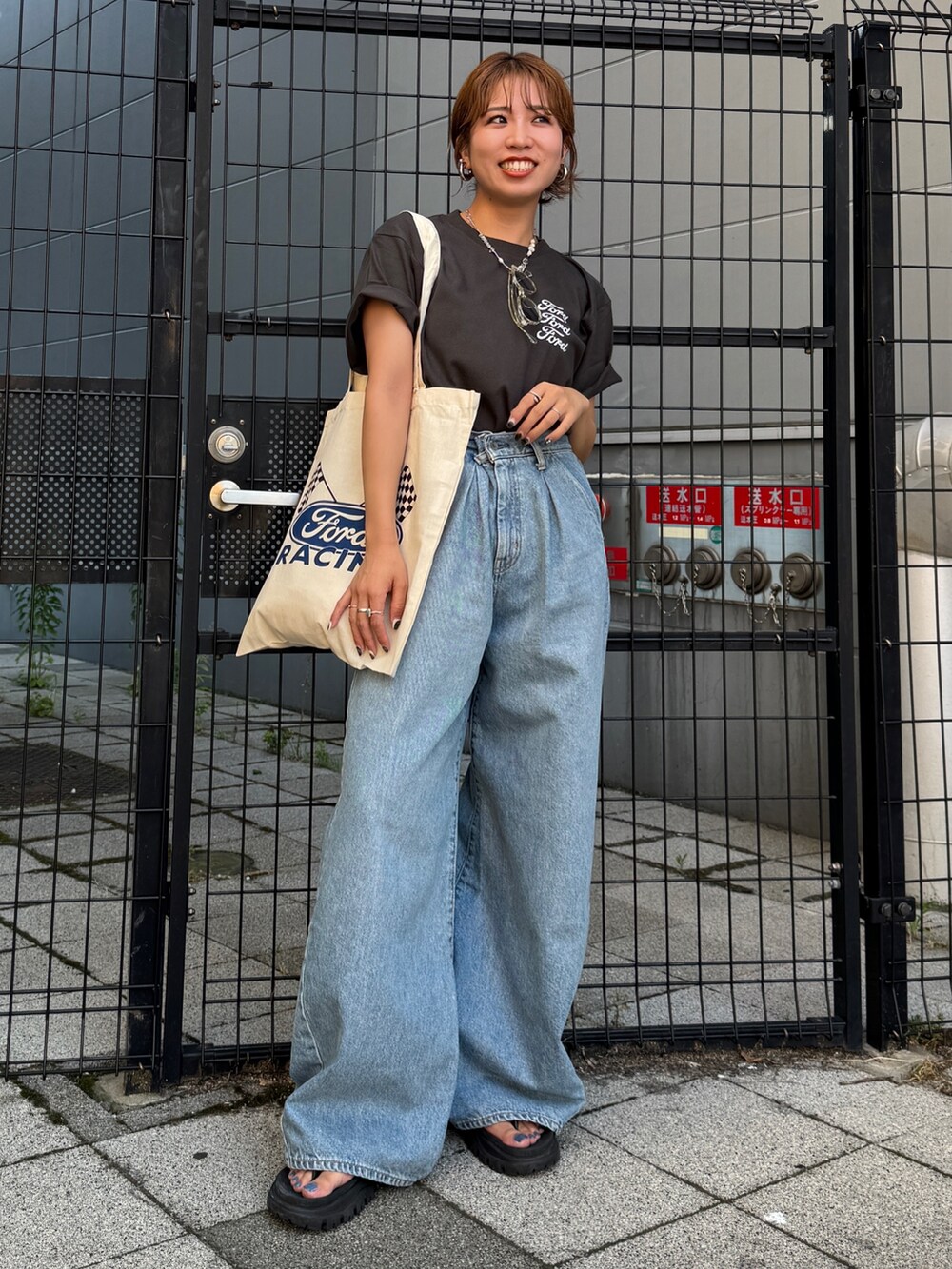 ブルー系のデニムパンツ、グレー系のTシャツ/カットソー、ホワイト系のトートバッグを着用したレディースの夏コーディネートの3枚目の写真