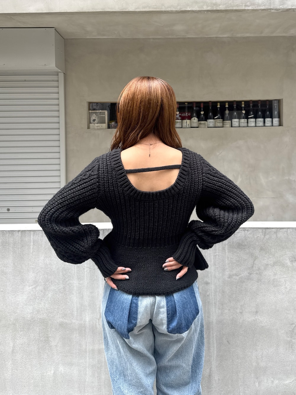 ブラック系のニット/セーター、ブルー系のデニムパンツ、ブラック系のサンダルを着用したレディースの秋コーディネートの6枚目の写真