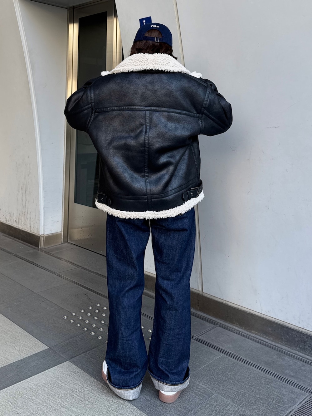 ブルー系のデニムパンツ、ホワイト系のカーディガン/ボレロ、ブラック系のブルゾンを着用したレディースの冬コーディネートの4枚目の写真