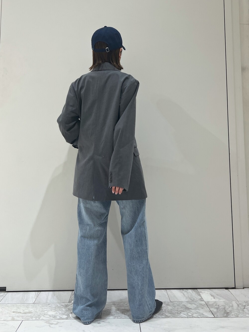 グレー系のテーラードジャケット、ブルー系のデニムパンツ、ブラック系のパンプスを着用したレディースの冬コーディネートの4枚目の写真