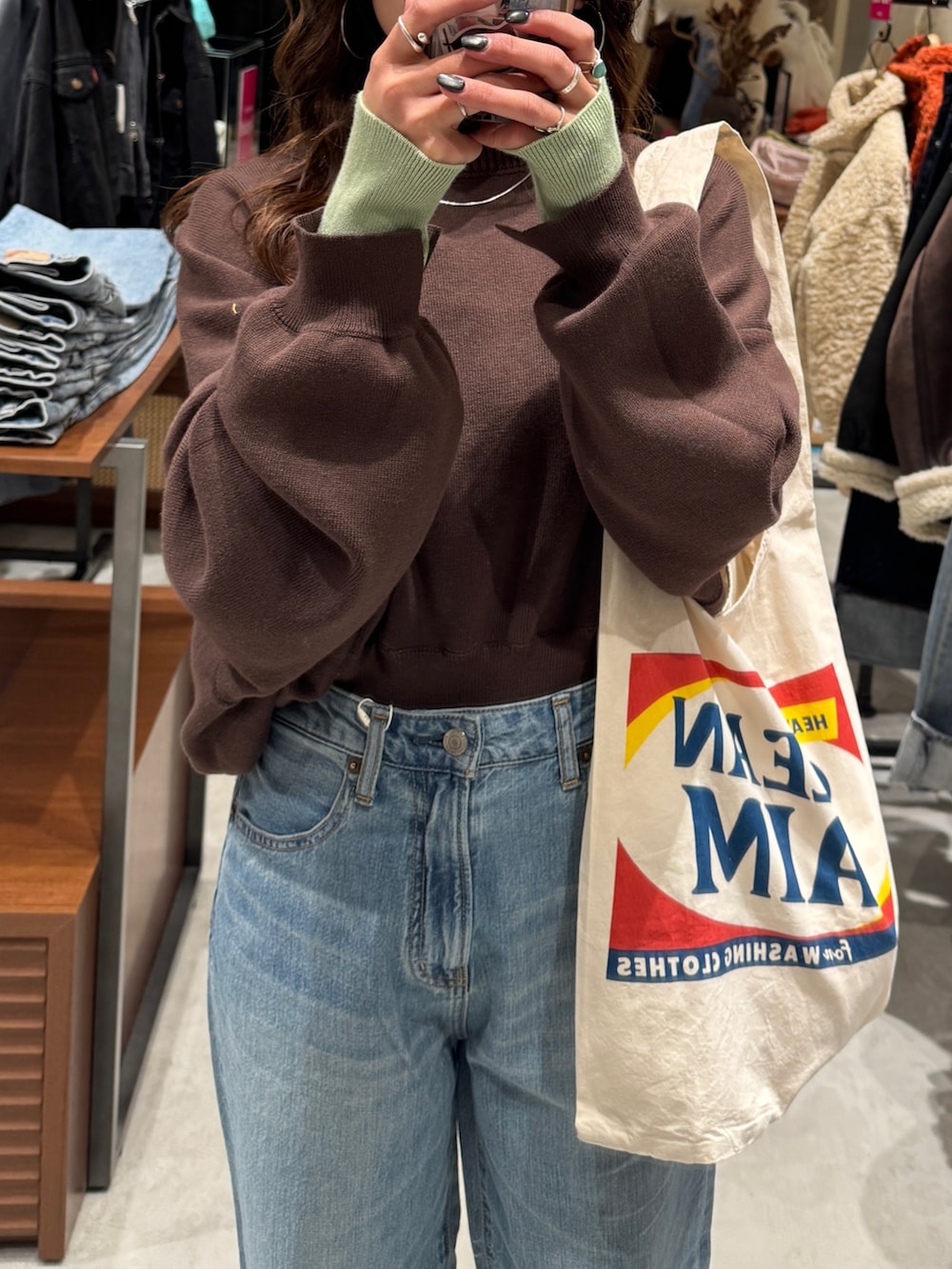 ブルー系のデニムパンツ、ブラウン系のニット/セーター、ホワイト系のトートバッグを着用したレディースの冬コーディネートの8枚目の写真