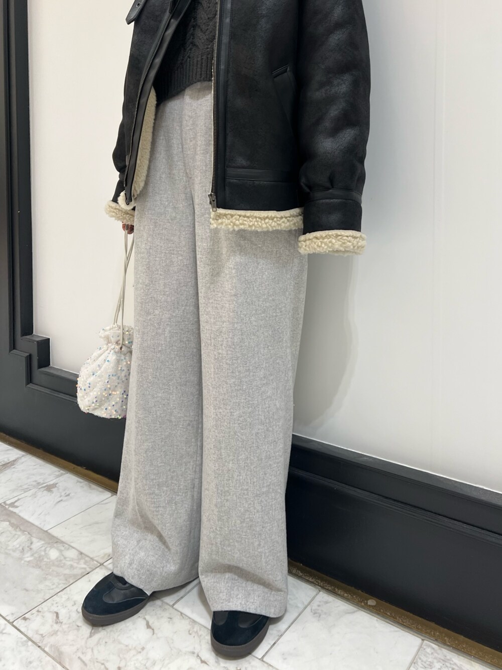 ホワイト系のハンドバッグ、グレー系のニット/セーター、ブラック系のムートンコートを着用したレディースの冬コーディネートの5枚目の写真