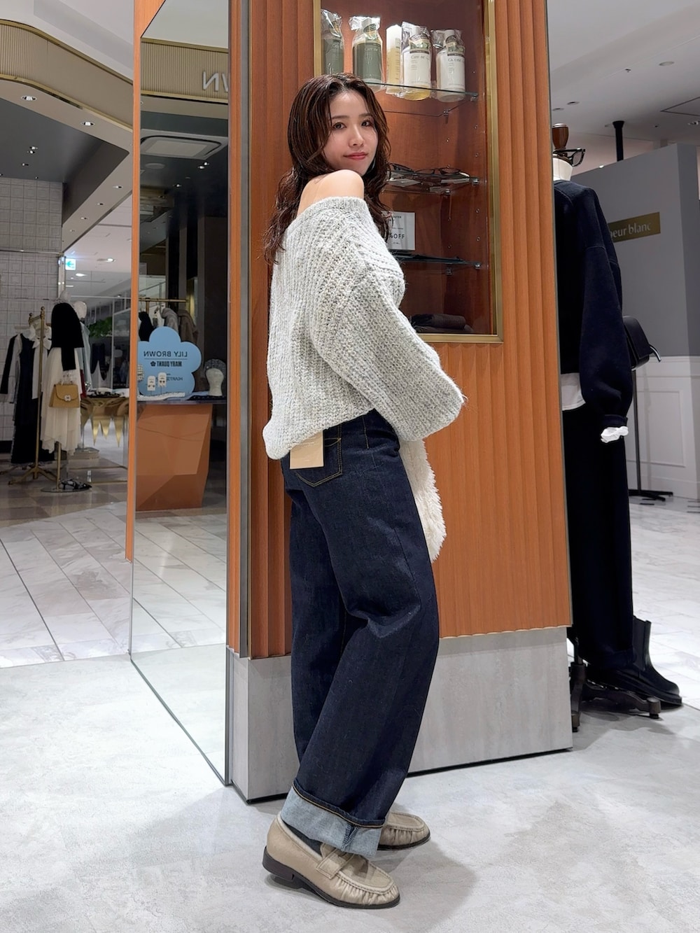 グレー系のニット/セーター、ブルー系のデニムパンツ、ホワイト系のハンドバッグを着用したレディースの冬コーディネートの2枚目の写真