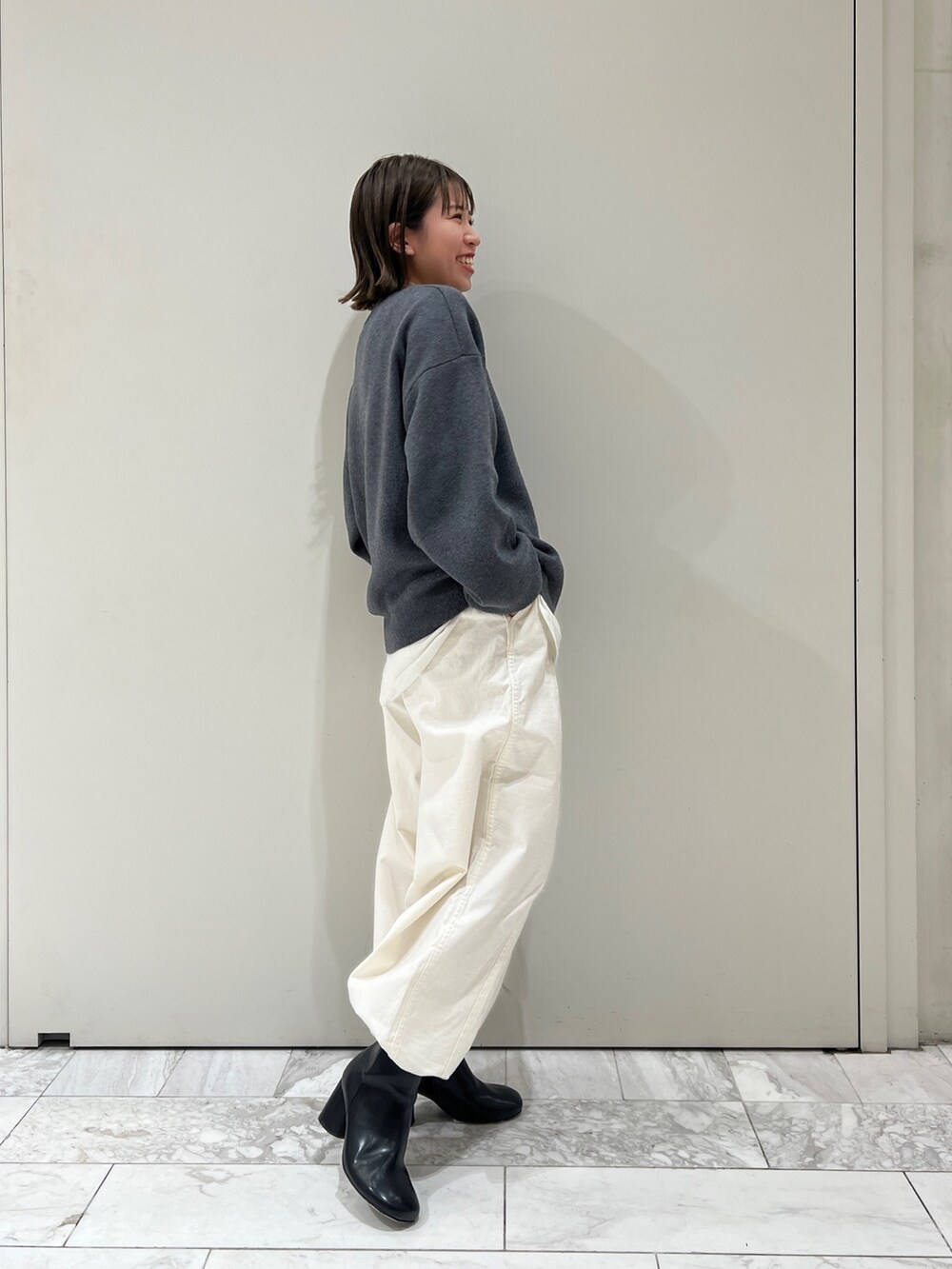 グレー系のニット/セーター、ホワイト系のTシャツ/カットソー、ホワイト系のその他パンツを着用したレディースの冬コーディネートの4枚目の写真