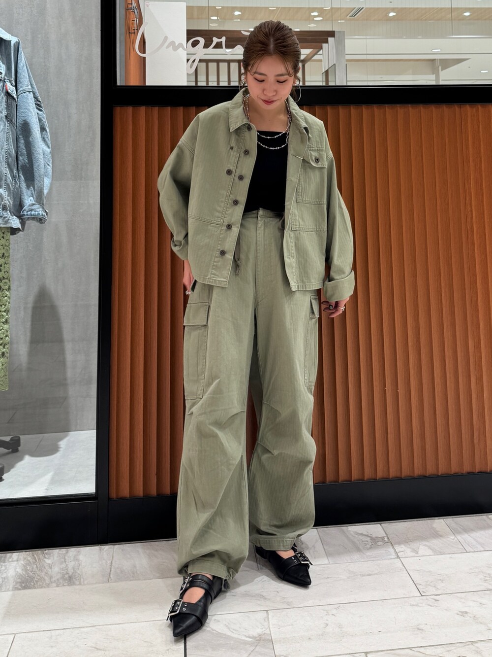 グリーン系のミリタリージャケット、ブラック系のキャミソール、グリーン系のその他パンツを着用したレディースの春コーディネートの2枚目の写真