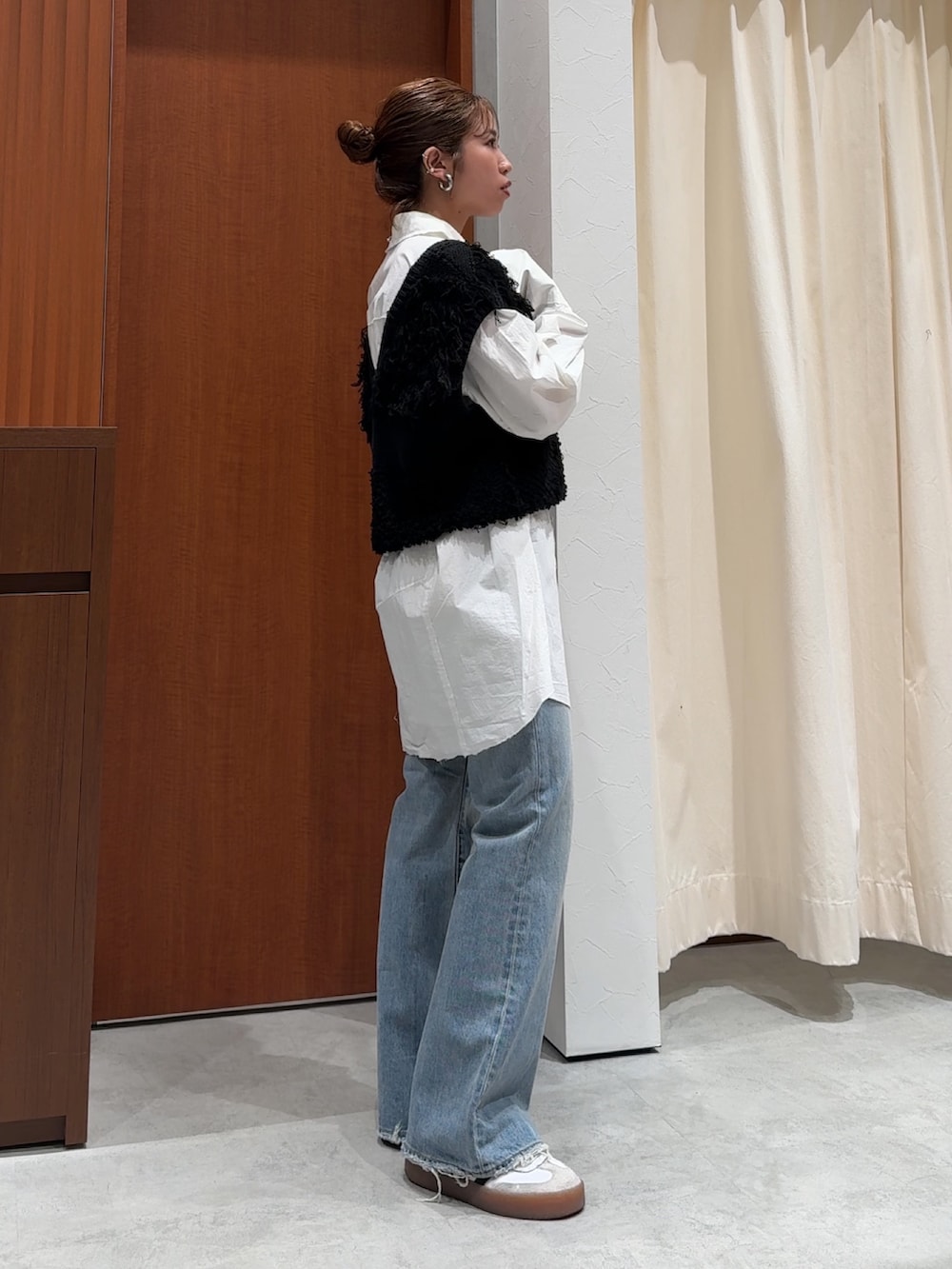 ブラック系のベスト、ホワイト系のシャツ/ブラウス、ブルー系のデニムパンツを着用したレディースの春コーディネートの4枚目の写真