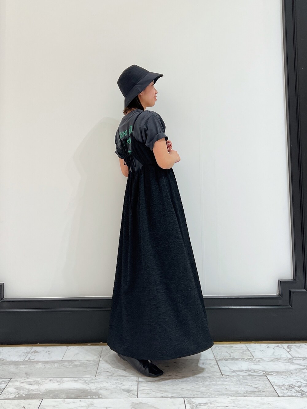 ブラック系のワンピース、グレー系のTシャツ/カットソー、ブラック系のパンプスを着用したレディースの春コーディネートの2枚目の写真