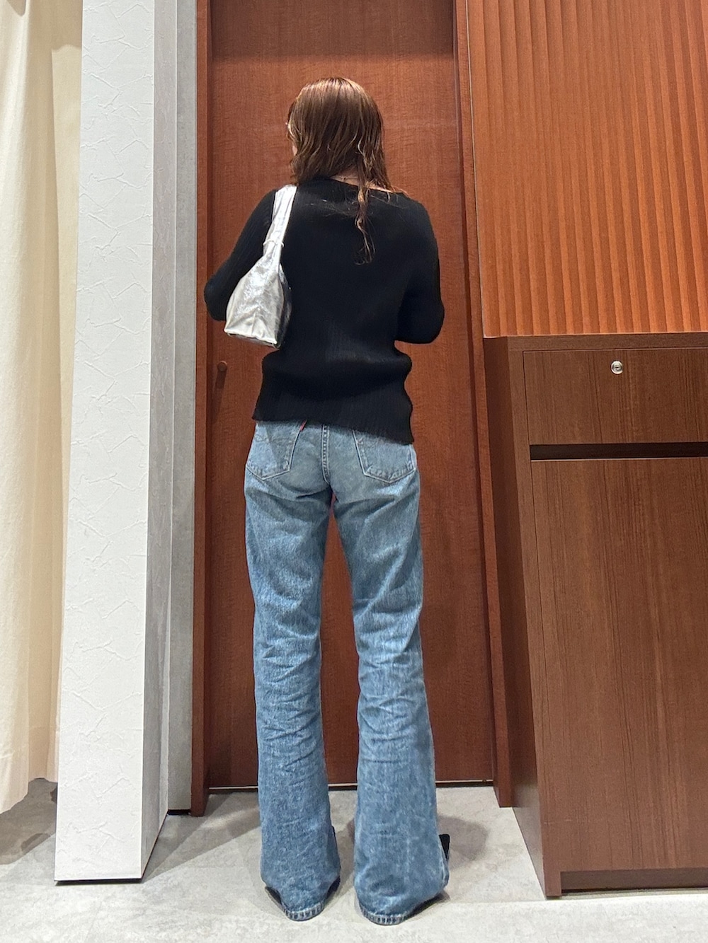 ブルー系のデニムパンツ、ブラック系のカーディガン/ボレロ、ブラック系のパンプスを着用したレディースの春コーディネートの3枚目の写真