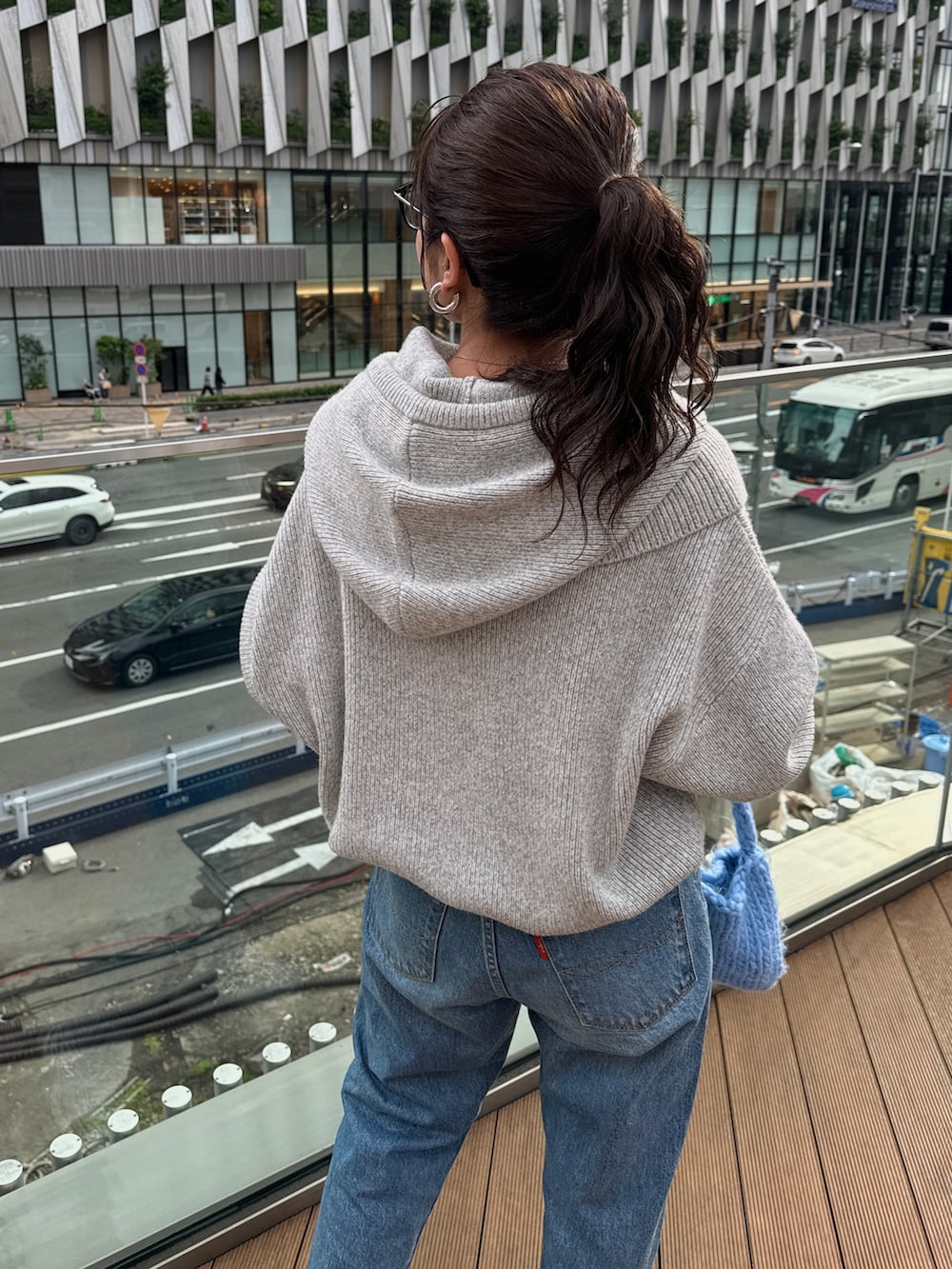 ブルー系のハンドバッグ、グレー系のニット/セーター、ブルー系のデニムパンツを着用したレディースの秋コーディネートの5枚目の写真