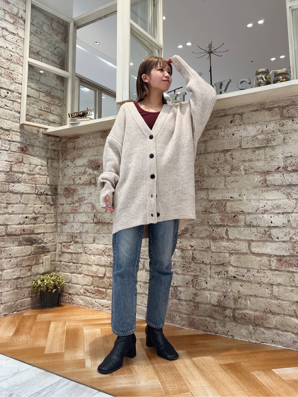 ブラック系のブーツ、ブルー系のデニムパンツ、ホワイト系のカーディガン/ボレロを着用したレディースの秋コーディネートの6枚目の写真