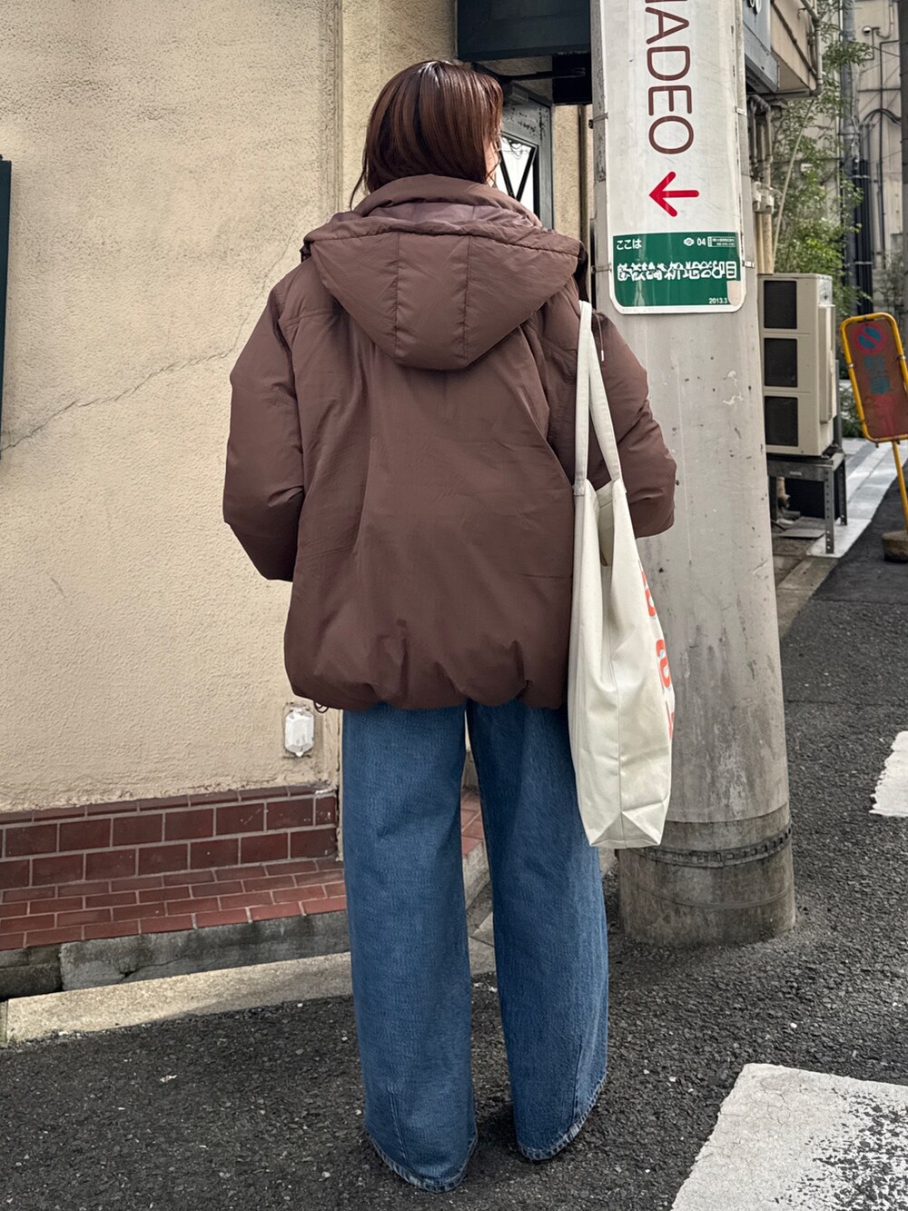 ブラウン系のダウンジャケット/コート、ホワイト系のニット/セーター、ブルー系のデニムパンツを着用したレディースの秋コーディネートの6枚目の写真