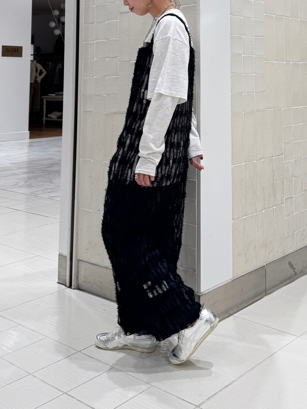 ブラック系のワンピース、グレー系のTシャツ/カットソー、ブルー系のデニムパンツを着用したレディースの春コーディネートの7枚目の写真