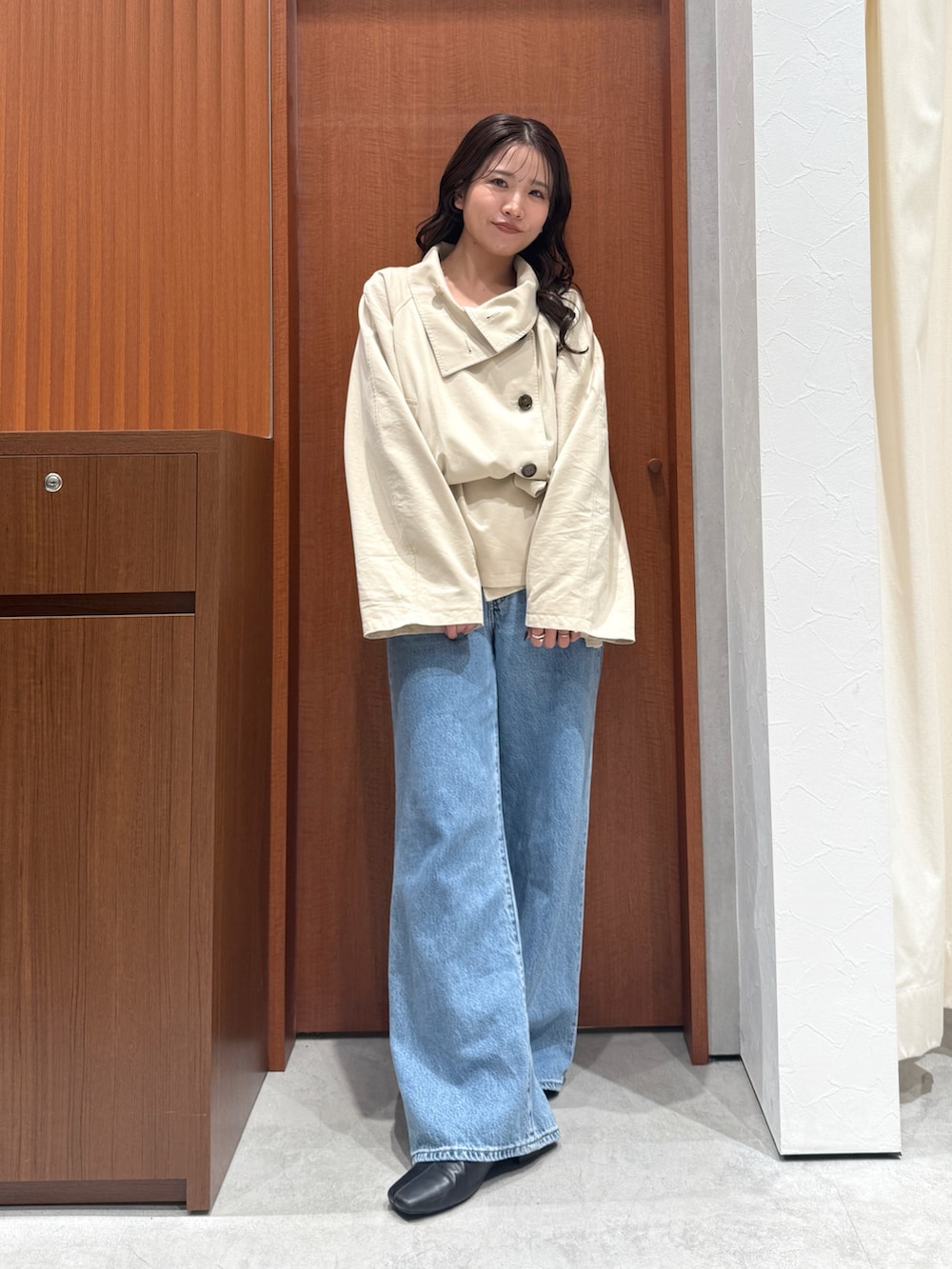 ベージュ系のトレンチコート、ブルー系のデニムパンツ、ブラック系のサンダルを着用したレディースの秋コーディネートの6枚目の写真