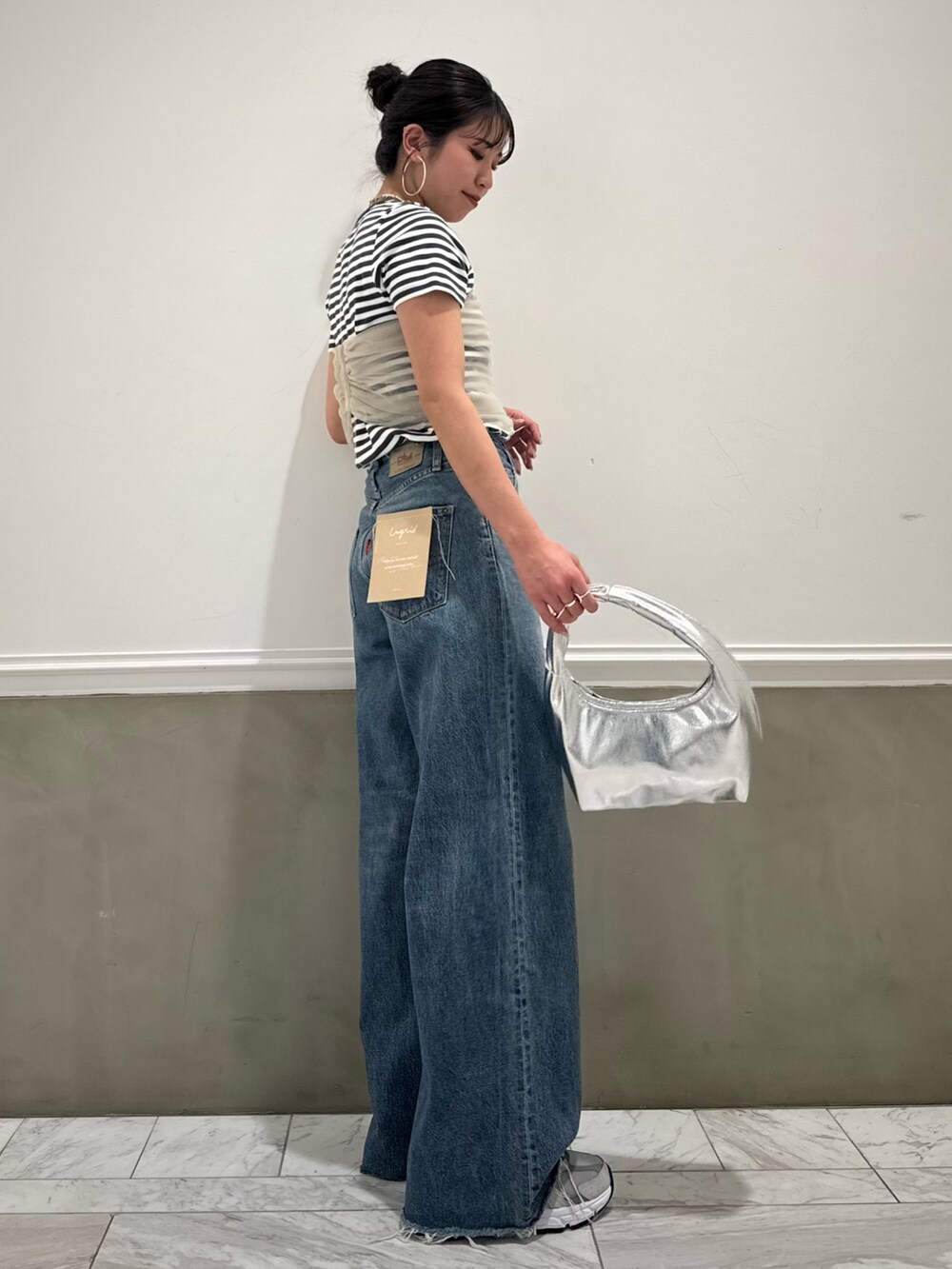 グレー系のTシャツ/カットソー、ベージュ系のキャミソール、ブルー系のデニムパンツを着用したレディースの春コーディネートの2枚目の写真