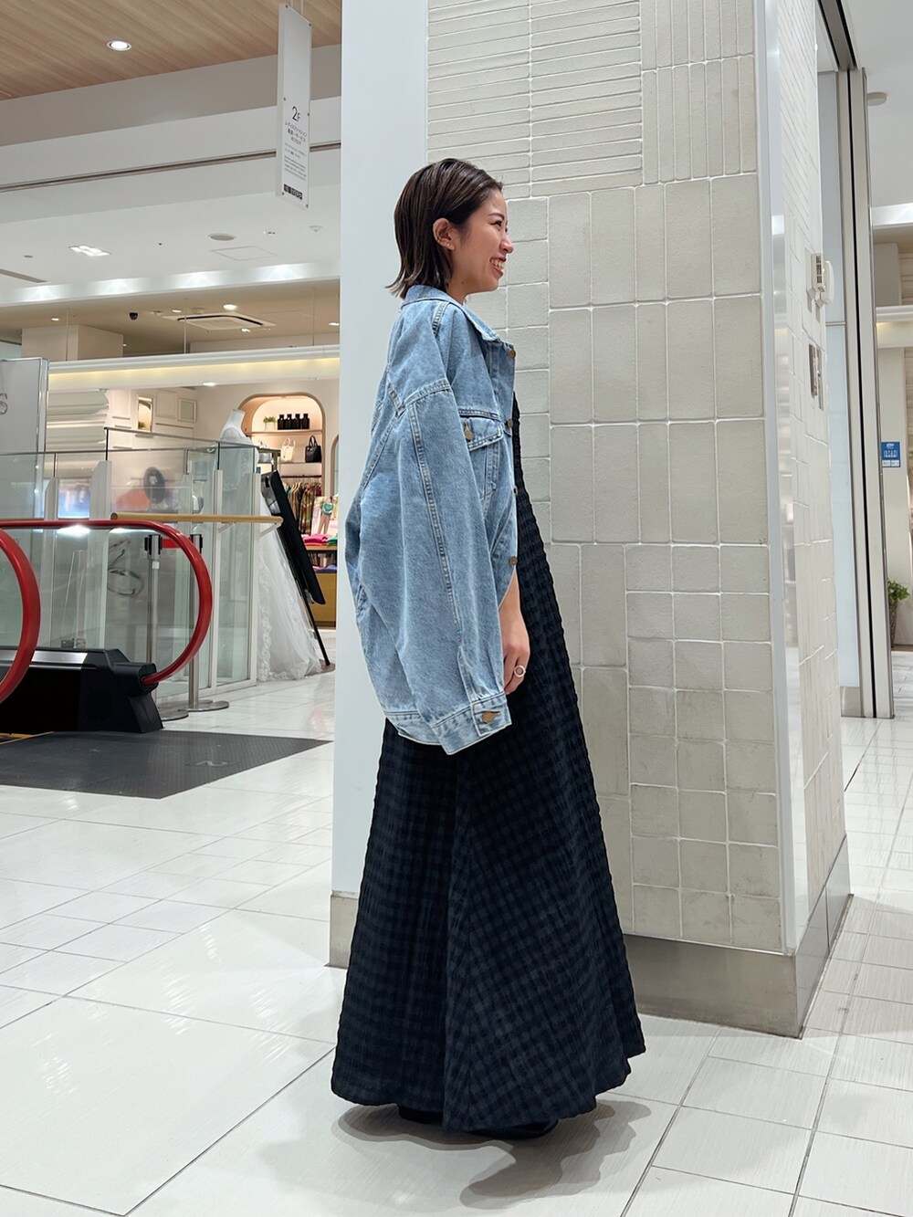 ブラック系のワンピース、グリーン系のタンクトップ、ブルー系のデニムジャケットを着用したレディースの冬コーディネートの6枚目の写真